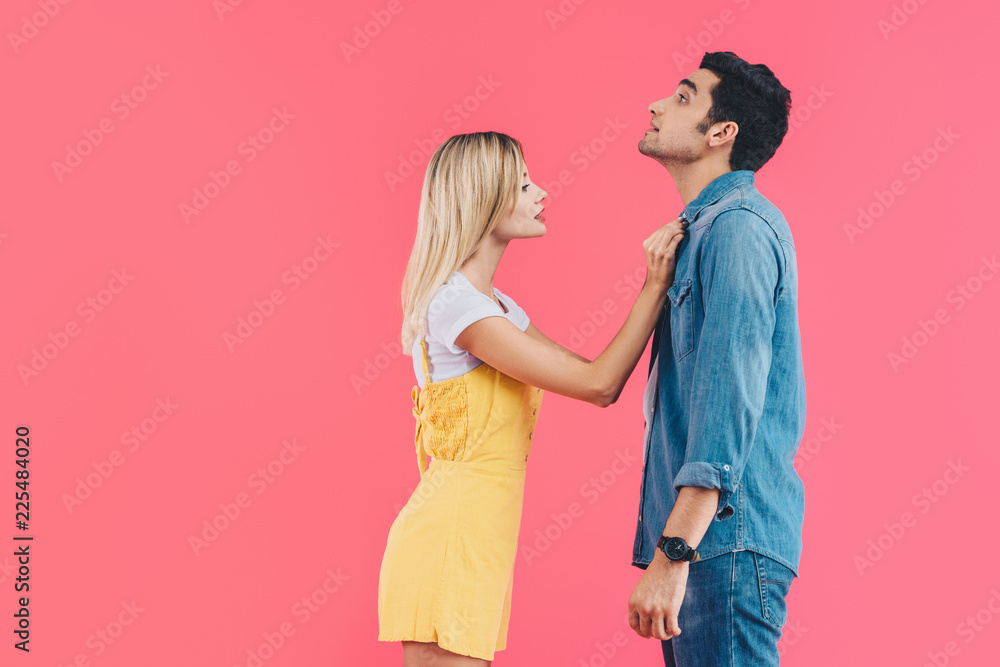 side view of beautiful woman fastening boyfriends shirt isolated on pink side view of beautiful woman fastening boyfriends shirt isolated on pink