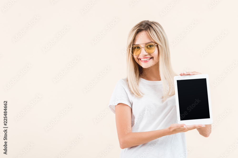 happy young woman in eyeglasses showing digital tablet with blank screen isolated on beige happy young woman in eyeglasses showing digital tablet with blank screen isolated on beige