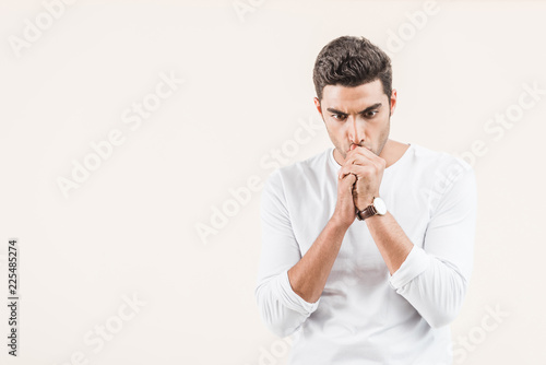 focused young man thinking and looking down isolated on beige © LIGHTFIELD STUDIOS