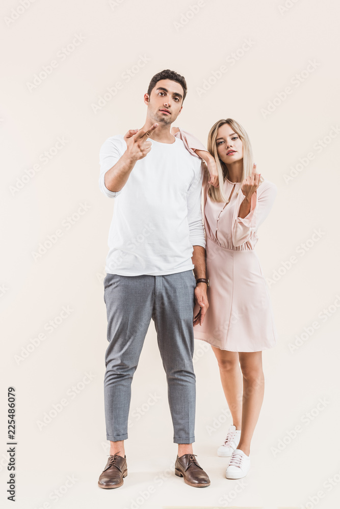 aggressive young couple giving the fingers and looking at camera isolated on beige aggressive young couple giving the fingers and looking at camera isolated on beige