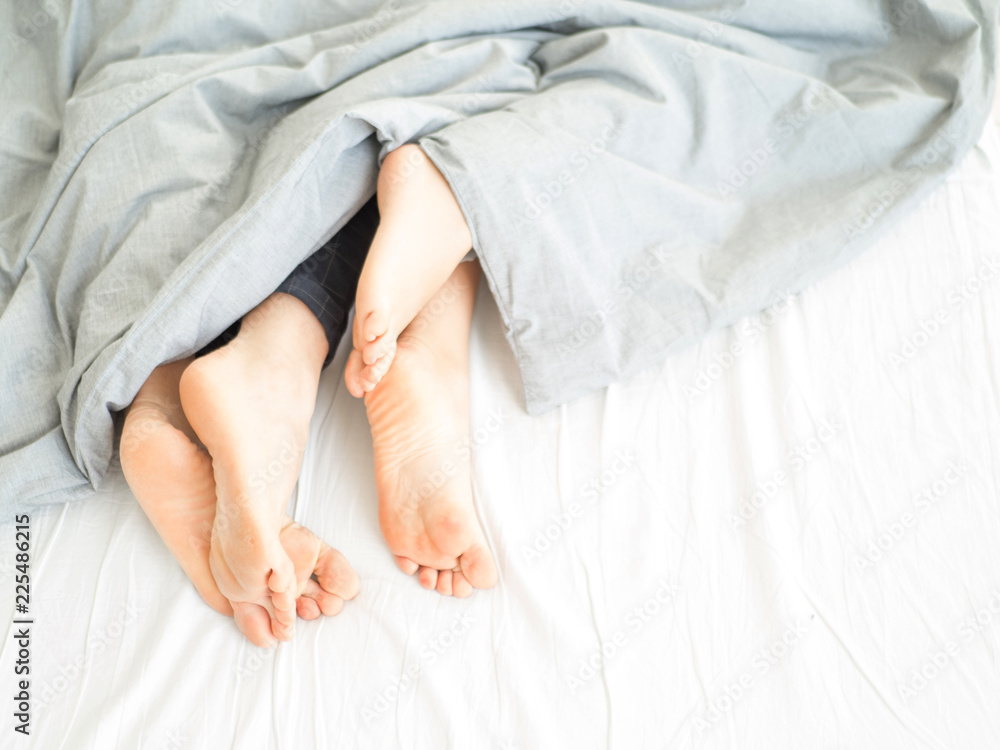 Couple on white bed in hotel room focus at feet. Couple on white bed in hotel room focus at feet.