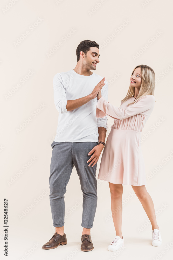 happy young couple giving high five and smiling each other isolated on beige happy young couple giving high five and smiling each other isolated on beige
