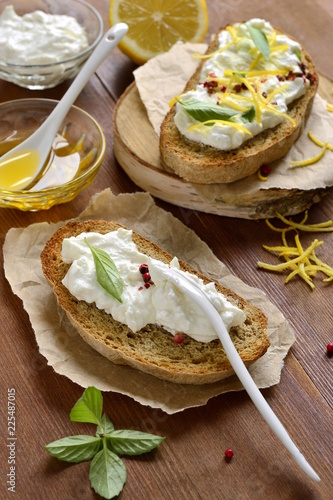 Lemon, basil, pink pepper, ricotta and honey bruschetta, vertical 