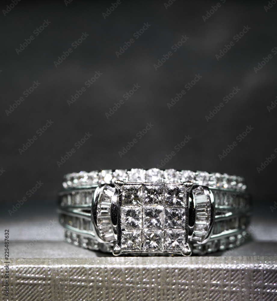 A diamond engagement ring in a box with glint/reflection. Shimmering princess-cut diamonds. A diamond engagement ring in a box with glint/reflection. Shimmering princess-cut diamonds.