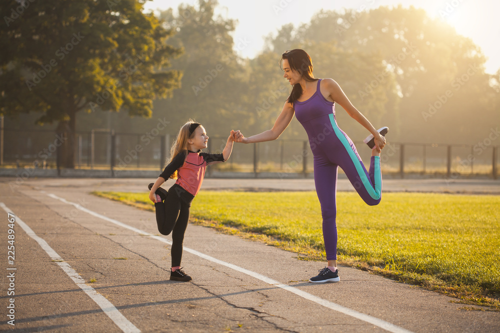 Fototapeta Mama i córka na porannym treningu sportowym rozgrzewają się. Zdrowy tryb życia