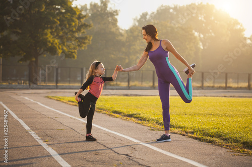 Fototapeta Naklejka Na Ścianę i Meble -  Mom and daughter on the morning sports training do a warm-up. Healthy lifestyle