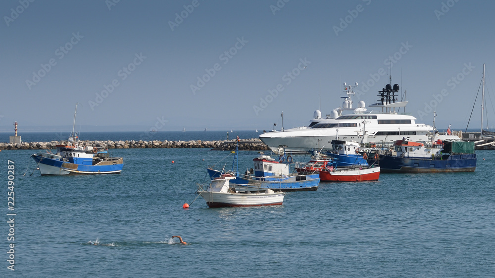 Fishing boats and luxury yacht docked at Cascais marina, near Lisbon, Portugal