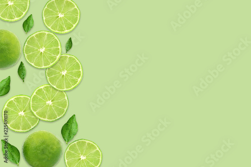 Pattern of citrus fruits.Fresh organic ripe lemon and lime with green leaves isolated on green background.Top view,flat lay with copy space empty blank for text.Food background, wallpaper. © Poh Smith