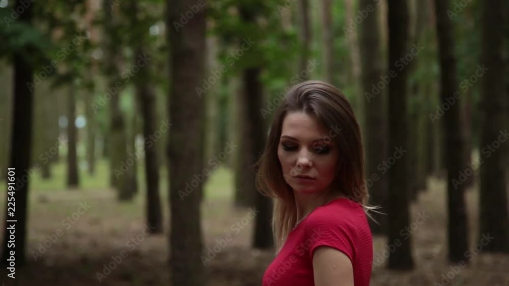 A very beautiful and fashionable woman in a red dress walks through the forest. A very beautiful and fashionable woman in a red dress walks through the forest.