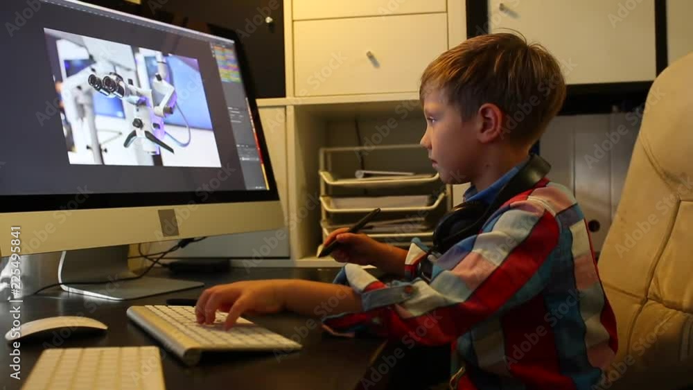 Smart Boy Works on a Project For His Computer. Boy works at the computer using a graphic tablet Smart Boy Works on a Project For His Computer. Boy works at the computer using a graphic tablet
