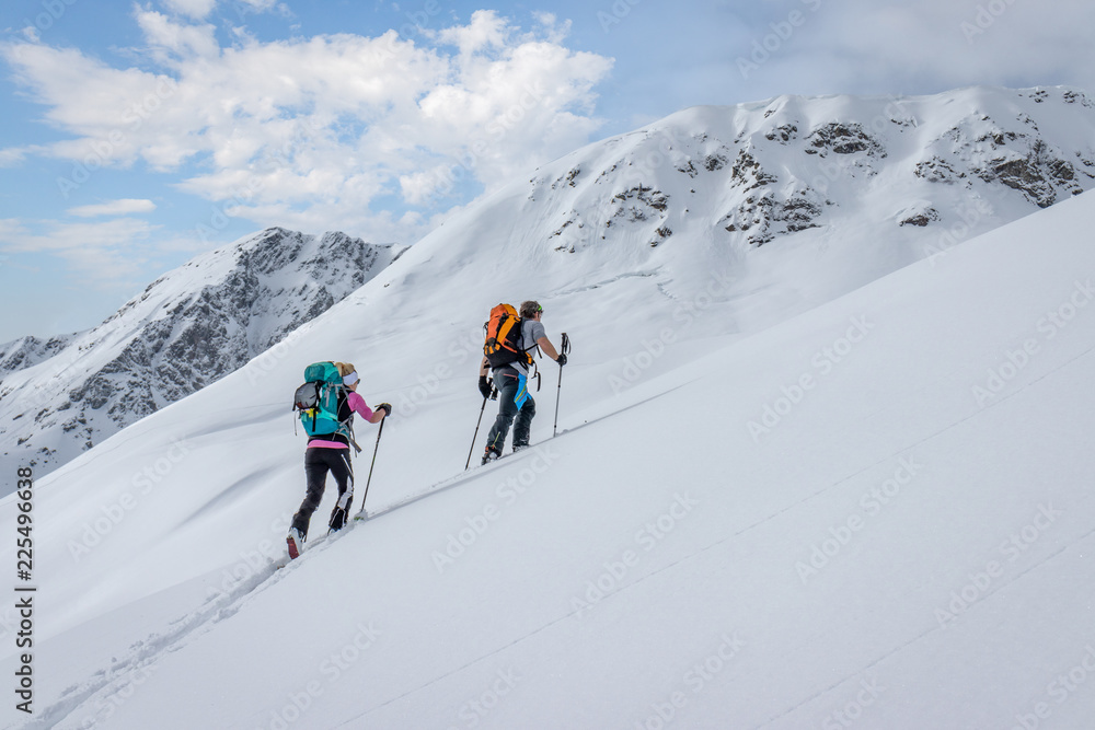 Ski touring couple hiking up a summit in the alps