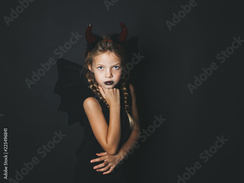 beautiful, blond girl is dressed as halloween devil with red horns and wings