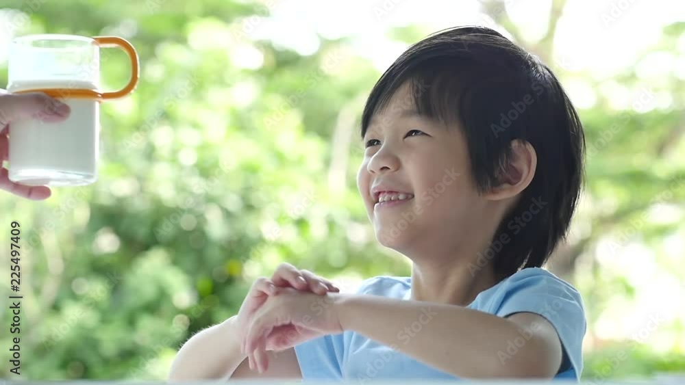 Cute asian child with a glass of milk and licking lip slow motion Cute asian child with a glass of milk and licking lip slow motion