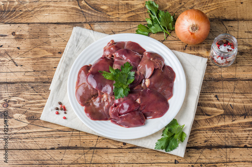 Fresh raw chicken liver on a plate. Wooden rustic background