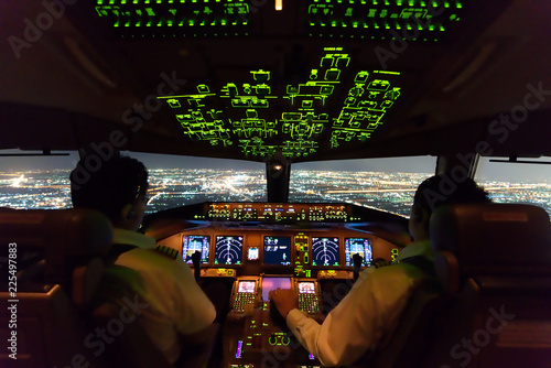 Vászonkép Asian airline pilots were operating commercial aircraft on approach phase over city on the night
