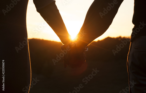 Romantic couple holding hands and watching a beautiful sunset