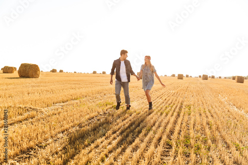 Happy young couple walking together at the wheat field
