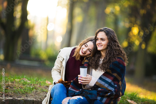 Two beautiful young women drinking coffee outdoors in the autmn