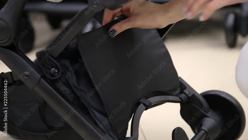 The process of folding a baby stroller in a children's store on the camera. The process of folding a baby stroller in a children's store on the camera.