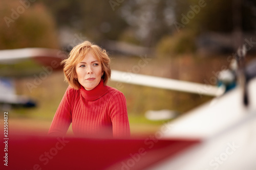 Beautiful girl in red dress and airplane. Walk at airport, autumn, photo