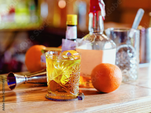 Old fashioned cocktail  orange  bottles and beaker on the bar counter