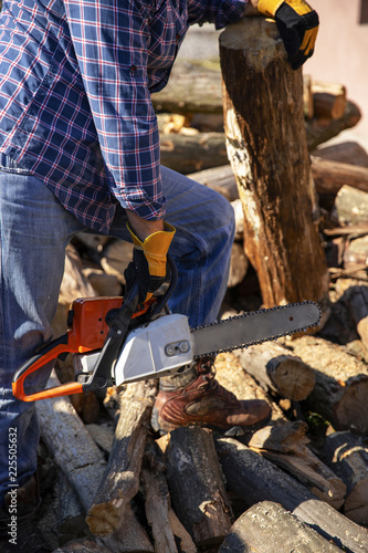 The worker works with a chainsaw. Chainsaw close up. Woodcutter saws tree with chainsaw on sawmill. Chainsaw in action cutting wood. Man cutting wood with saw, dust and movements.