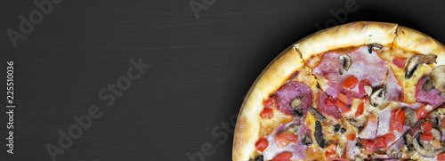 Freshly baked pizza on black background, view from above. Flat lay, overhead, top view. Copy space.