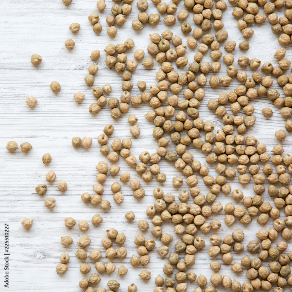 Dried chickpeas on a white wooden  background, overhead view.
