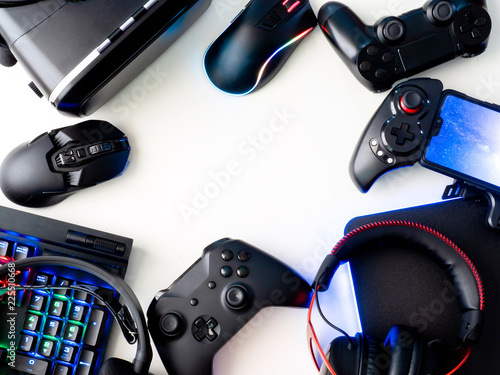 gamer workspace concept, top view a gaming gear, mouse, keyboard, joystick, headset, mobile joystick, in ear headphone and mouse pad on white table background. photo