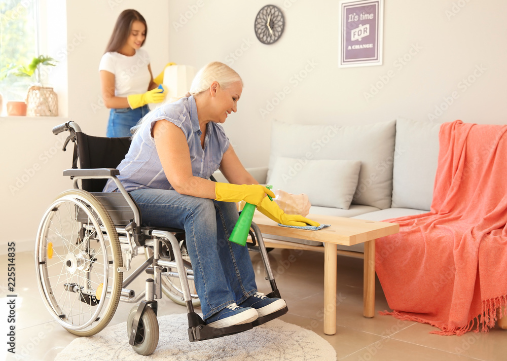 Mature woman in wheelchair cleaning table at home Mature woman in wheelchair cleaning table at home