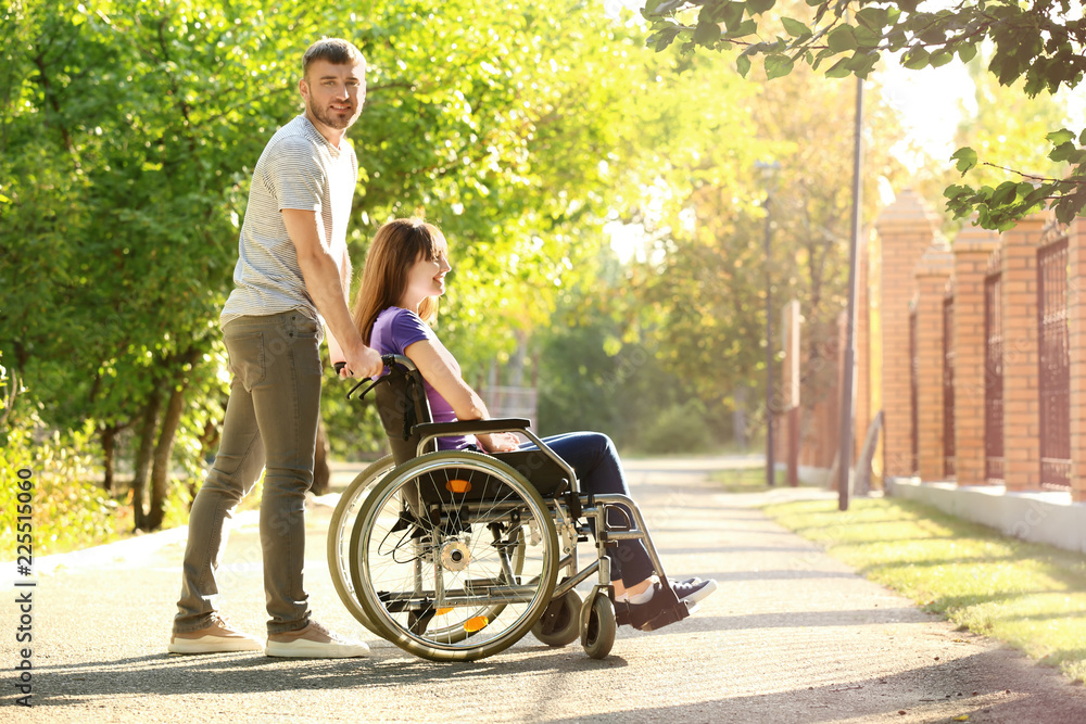 Young woman in wheelchair and her husband outdoors Young woman in wheelchair and her husband outdoors