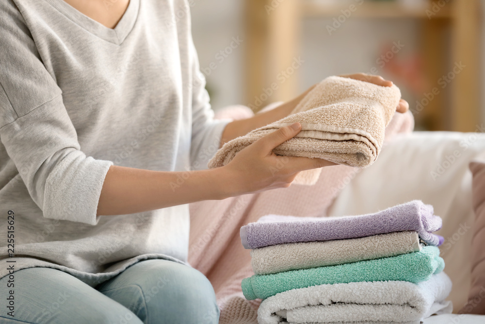 Woman stacking clean towels on sofa Woman stacking clean towels on sofa