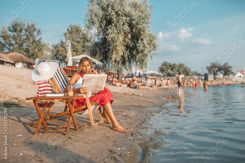Young woman reading newspaper on the beach
