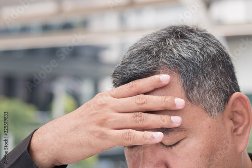 sick old senior man suffers from headahce; portrait of stressed, serious, sick old asian senior man with headache, migraine, vertigo, dizziness, stress, overwork; south east asian old senior man model
