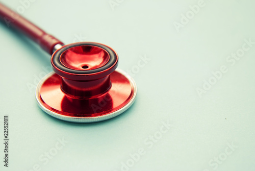 Red stethoscope on blue background. Close up. Medicine and healthcare. Copy space.