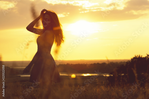 silhouette of a dreamy girl in a field at sunset, a young woman enjoying nature