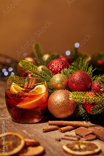 close up view of mulled wine drink in glass and pine tree with christmas toys on wooden surface