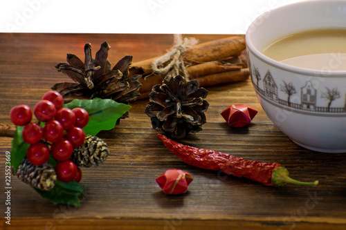 Fototapeta Naklejka Na Ścianę i Meble -  Coffee, spices and pine cones on a wooden background. Christmas concept. A cup of hot coffee with milk, cinnamon and chili on a wooden table.