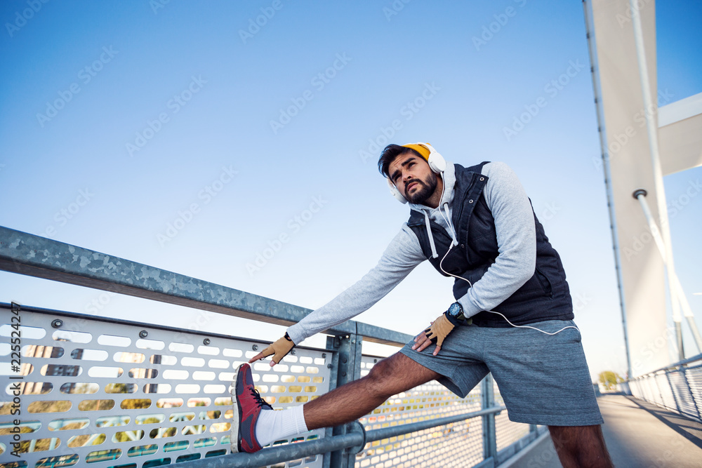Young active man doing stretching on the bridge before training