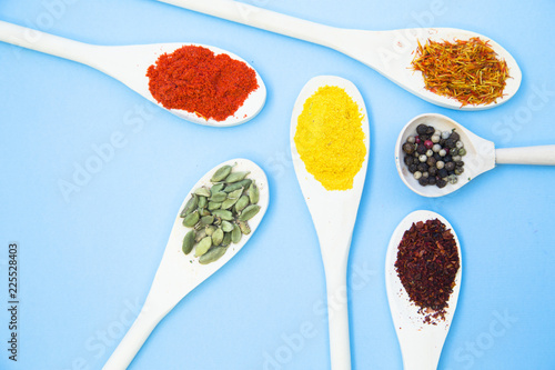 Cooking Hot Spicy Food Concept. Dry spices and herbs in wooden spoons, light blue background