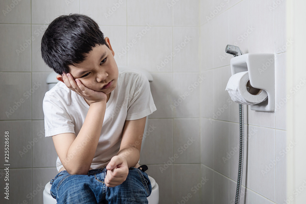 Asian boy sitting on toilet bowl - health problem concept Photos | Adobe  Stock