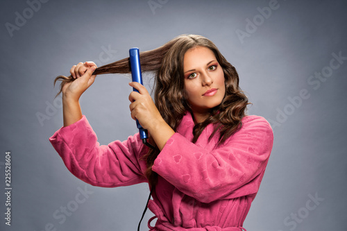Young brunette with hair straightener