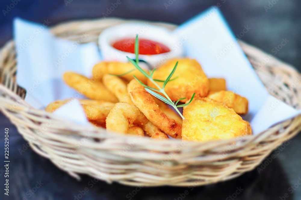 fried onion ring with chicken nuggets in a beautiful wodden basket with tomato ketchup