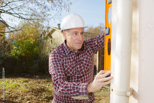 builder checking the straightness of drainpipe photo