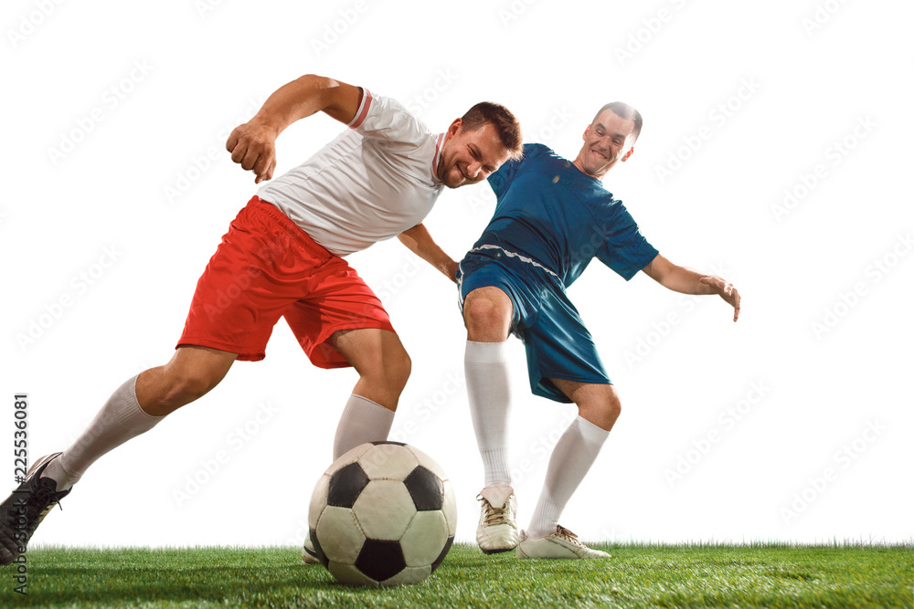 Football players tackling for the ball over white background. Professional football soccer players in motion isolated white studio background. Fit jumping men in action, jump, movement at game.