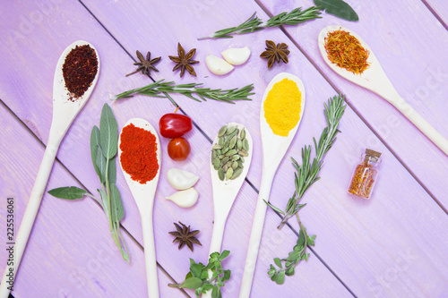 Cooking Hot Spicy Food Concept. Dry spices,beans and herbs in plastic cup, glass jar with cork and wooden spoon, purple wooden background photo