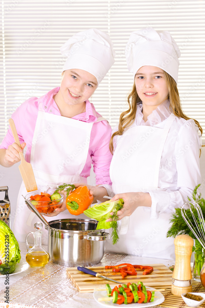 Portrait of two cute girls cooking on kitchen