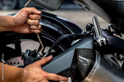 Image is Close up,People are repairing a motorcycle Use a wrench and a screwdriver to work. © Suppasit