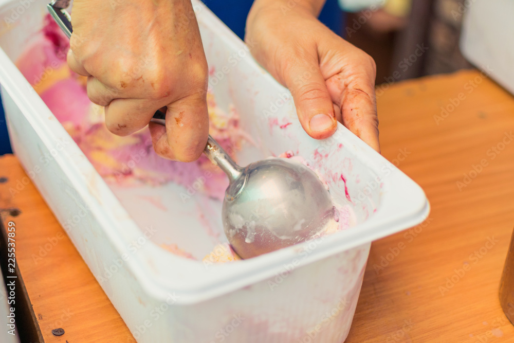 The hand puts an ice cream ball from the container.