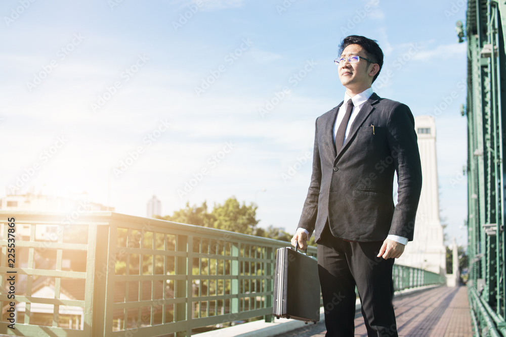 confidential business man standing and holding bag, investor walking and looking forward on road confidential business man standing and holding bag, investor walking and looking forward on road